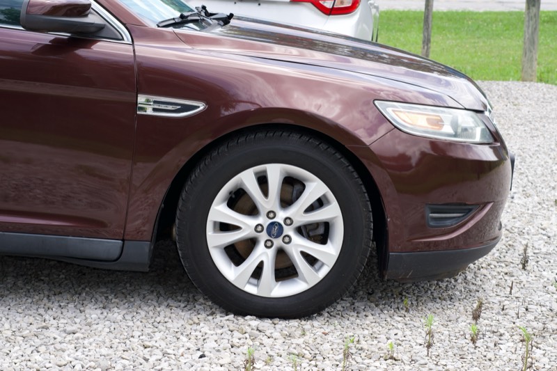 Maroon Ford Taurus SEL, front wheel and headlight detail